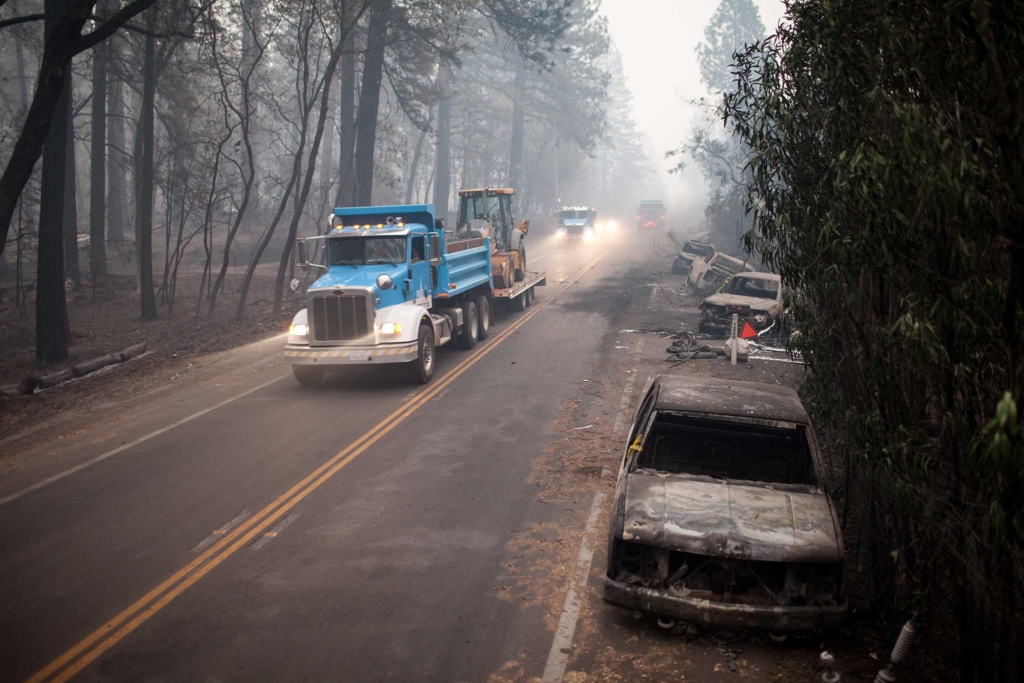 PG&E vehicles drive past burnt cars in Paradise, California, three days after the Camp Fire in November 2018. Photo: Joel Angel Juarez / Zuma Press