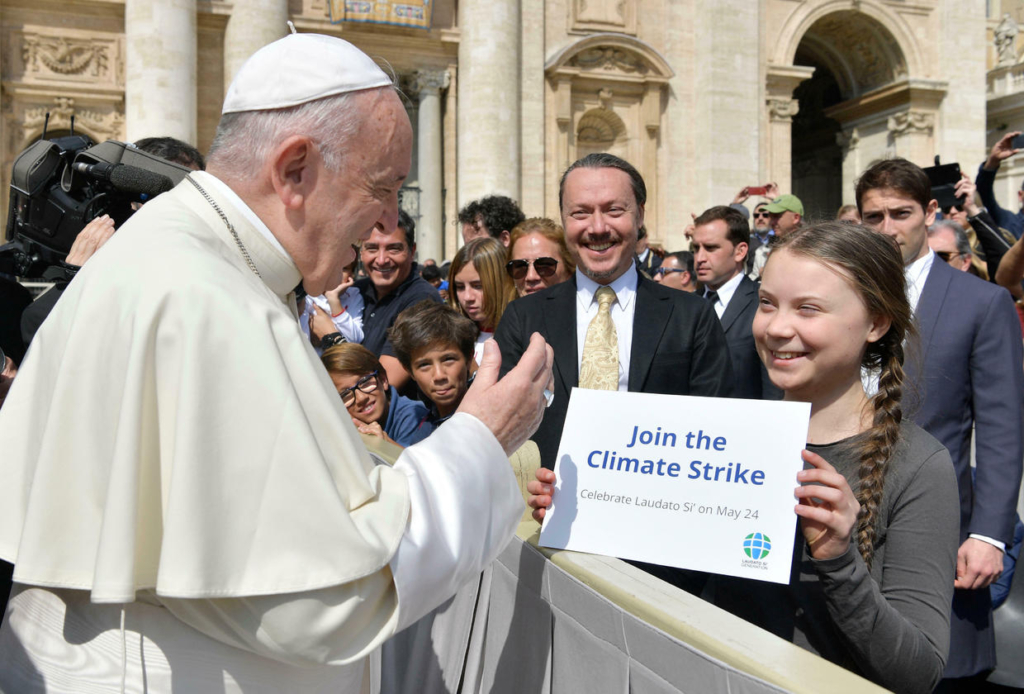 Swedish teenage environmental activist Greta Thunberg holds up a sign as Pope Francis greets her at the end of his weekly general audience, in St. Peter's Square, at the Vatican, on 17 April 2019. Photo: AP