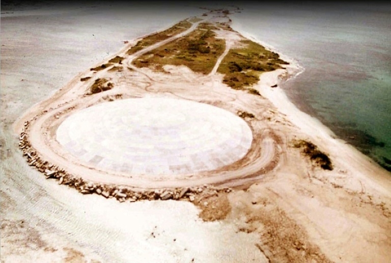 Aerial view of the nuclear waste dome built two decades after the U.S. "Cactus" nuclear bomb test in May 1958. The U.S. military filled the bomb crater on Runit island with radioactive waste, capped it with concrete, and told displaced residents of the Pacific's remote Enewetak atoll they could safely return home. But Runit's 45-centimetre (18-inch) thick concrete dome has now developed cracks. Photo: Giff Johnson / U.S. Defense Nuclear Agency / AFP