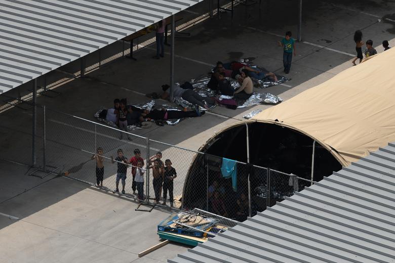 Migrants are seen outside the U.S. Border Patrol McAllen Station in a makeshift encampment in McAllen, Texas, 15 May 2019.  “From what we’ve seen at McAllen, people are sleeping on rocks and stones, and without shelter,” said Erika Andiola, chief advocacy officer at the Refugee and Immigrant Center for Education and Legal Services (RAICES), which provides legal services to migrants. Photo: Loren Elliott / Reuters