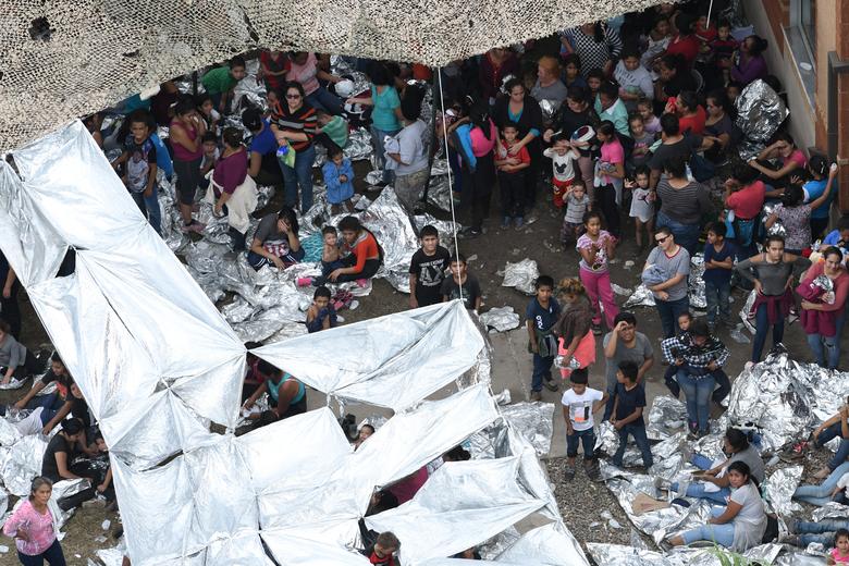 Migrants are seen outside the U.S. Border Patrol McAllen Station in a makeshift encampment in McAllen, Texas, 15 May 2019. Adults and children slept on the ground and rigged up makeshift awnings with reflective blankets to shelter from the sun. Photo: Loren Elliott / REUTERS