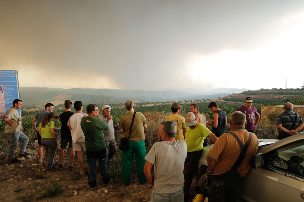 People watch smoke rise from a wildfire burning near Mials, in the northeastern Spanish region of Catalonia on 27 June 2019. Officials said up to 50,000 acres were threatened. Photo: Pau Barrena / Agence France-Presse