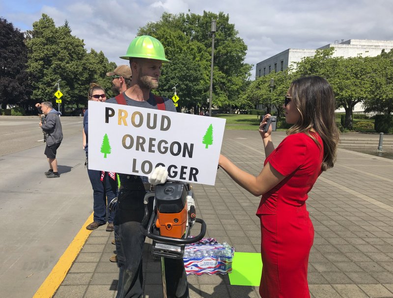 A TV reporter interviews self-employed logger Bridger Hasbrouck, of Dallas, Oregon, outside the Oregon State House in Salem, Oregon, on Thursday, 20 June 2019, the day the Senate is scheduled to take up a bill that would create the nation's second cap-and-trade program to curb carbon emissions. Senate Republicans, however, walked out so there wouldn't be enough lawmakers present for a vote on House Bill 2020, which is extremely unpopular among loggers, truckers and many rural voters. Photo: Gillian Flaccus / AP Photo