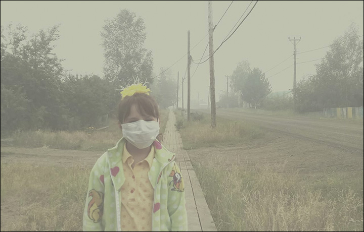 A child wears a mask because of pollution from widespread forest fires near her settlement of Vanavara, Krasnoyarsk Krai, Russia, on 29 July 2019. Photo: The Siberian Times