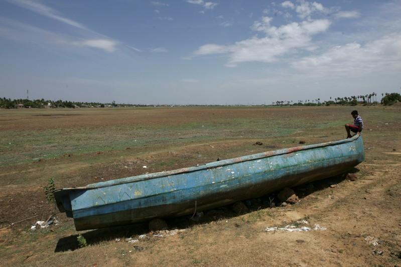 A man sits on a fishing boat stranded on the bed of dried-up lake in Thiruninravur, India, 29 June 2019. Photo: P. Ravikumar / REUTERS
