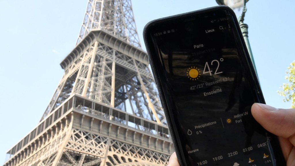 A person standing next to the Eiffel Tower holds a smartphone showing a temperature of 42 degrees Celsius (107 degrees Fahrenheit), on 25 July 2019 in Paris, during Europe’s record-breaking heatwave. Photo: Bertrand Guay / AFP / Getty Images