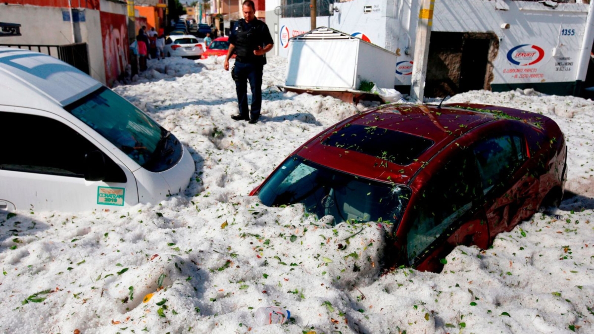A policeman stands next to vehicles buried in hail in the eastern area of Guadalajara, Mexico, on 30 June 2019. Photo: Ulises Ruiz / AFP / Getty Images