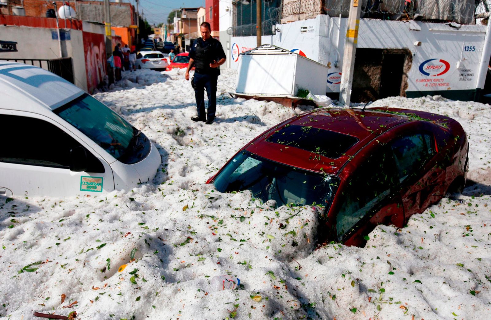 A policeman stands next to vehicles buried in hail in the eastern area of Guadalajara, Mexico, on 30 June 2019. Photo: Ulises Ruiz / AFP / Getty Images