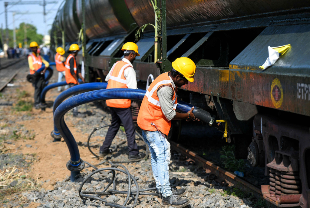 Workers connect pipes to collect water from a special train of 50 wagons carrying litres of water at Villivakkam railway station in Chennai, India on  12 July 2019. A special train took water to the major city of Chennai which has been reeling under its worst shortages in decades. The 50 wagons filled with 2.5 million litres of water were hauled by a locomotive decorated with flowers and a  “Drinking Water for Chennai” banner on the front at the start of the trip. Photo: Arun Sankar / AFP / Getty Images