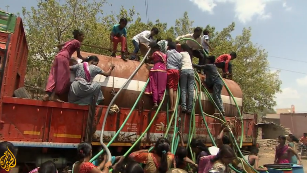 Villagers in Maharashtra state climb on a water truck to attach hoses for their daily water supply during India’s crippling drought of 2019. Photo: Al Jazeera