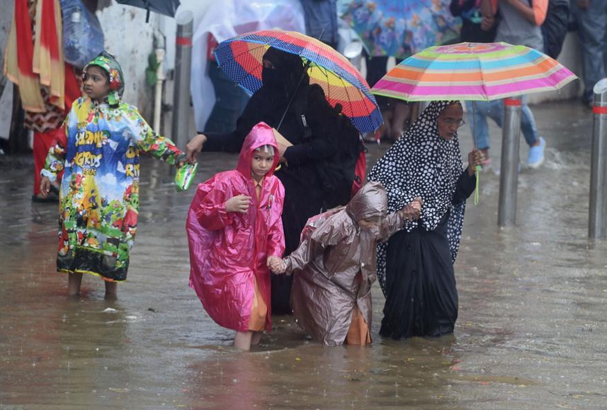 Women and children wade through a flooded street during monsoon rain in Mumbai, July 2019. Photo: PTI