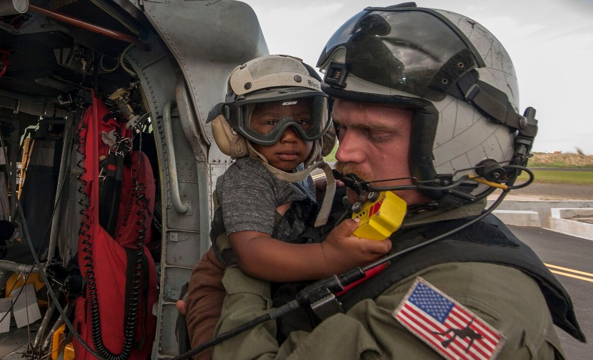 Naval Aircrewman (Helicopter) 2nd Class Brandon Larnard, from Helicopter Sea Combat Squadron 22, carries an evacuee in the wake of Hurricane Maria on the island of Dominica in 2017. The Navy recently did away with a task force dedicated to the effects of climate change, reversing an initiative by the Obama administration. Photo: Mass Communication Specialist 3rd Class Sean Galbreath / U.S. Navy