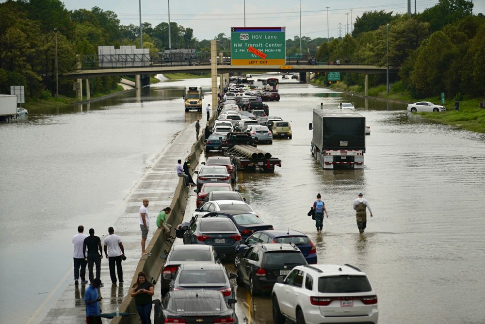 People wait outside of their stranded vehicles along Interstate 10 westbound at T.C. Jester, Thursday, 19 September 2019. The freeway is closed because of high water eastbound on the freeway from Tropical Storm Imelda. Photo: Mark Mulligan / Houston Chronicle / AP