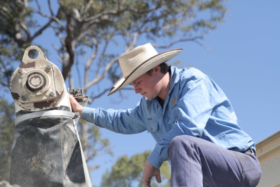 Cameron Saul, son of rancher Tony Saul, watches stockfeed they have had to buy being loaded into a feeder, on 15 September 2019. Farmers along Australia’s normally green eastern coast are reeling from the worst drought they have ever seen Photo: Jerry Rickard / ABC News