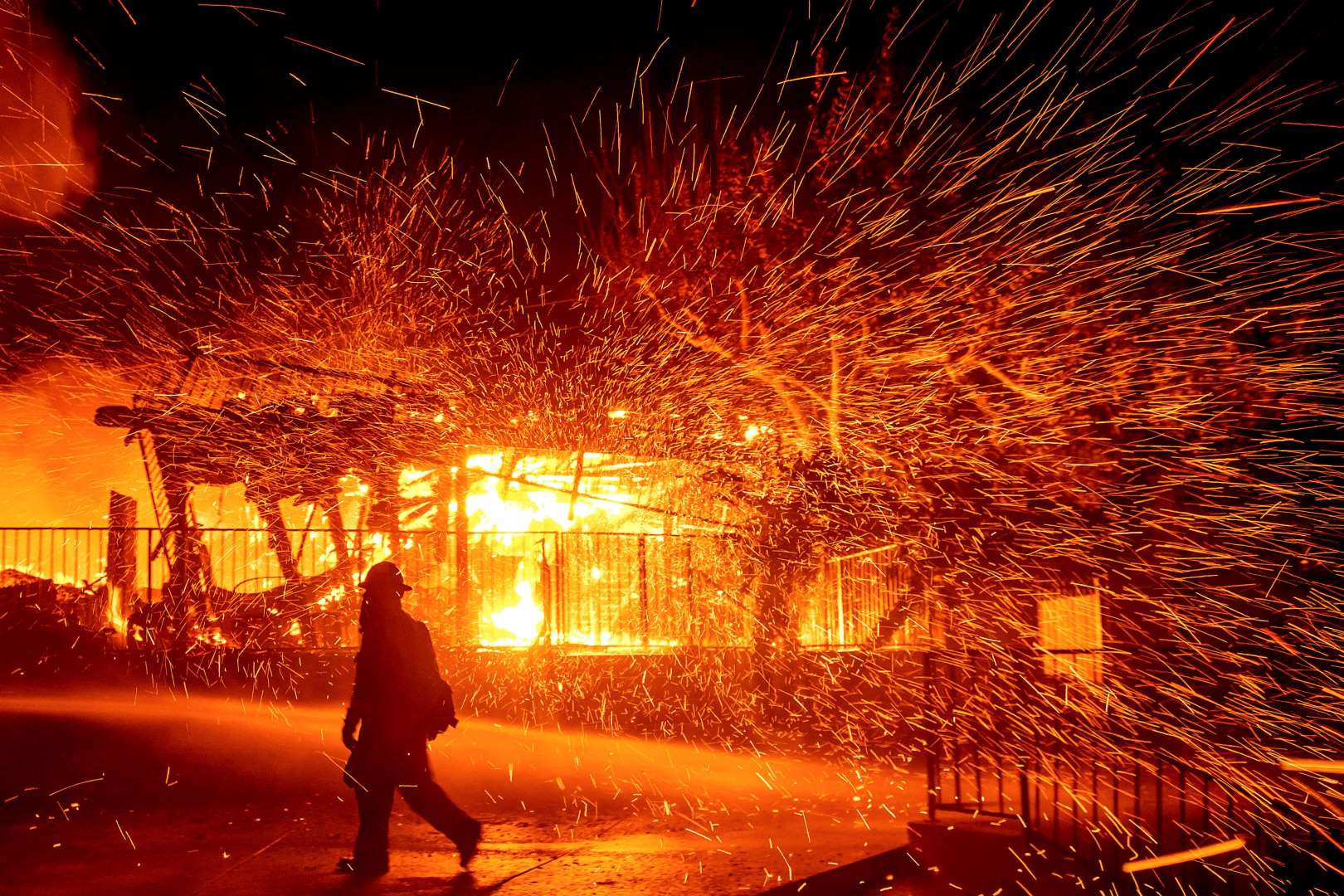 A firefighter passes a burning home as the Hillside fire burns in San Bernardino, California, on Thursday, 31 October 2019. The blaze, which ignited during red flag fire danger warnings, destroyed multiple residences. Photo: Noah Berger / AP Photo