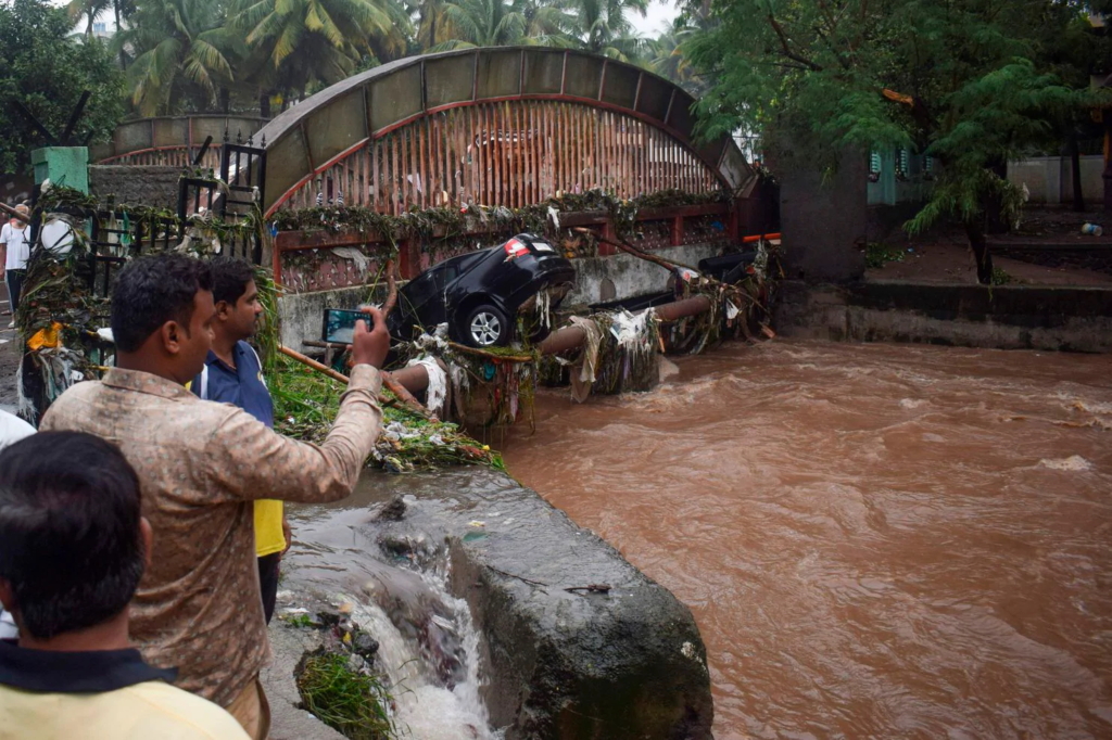 Onlookers and residents take photos of a car washed away by flash floods following heavy overnight rains in Pune on 26 September 2019. Photo: Jignesh Mistry / AFP / Getty Images