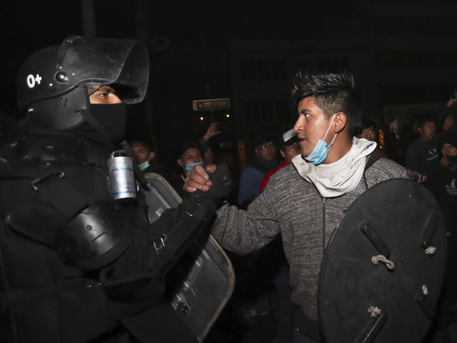 A protester shakes hands with a security officer in Quito, Ecuador, on Sunday, 13 October 2019, as they celebrate the government’s announcement that it has cancelled an austerity package and restored fuel subsidies. The package had triggered violent protests that paralyzed the economy and left seven people dead. Photo: Dolores Ochoa / AP