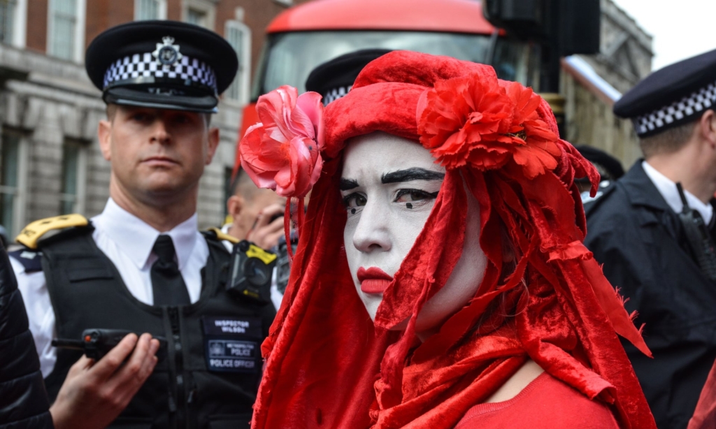 A protester wearing red stands in front of police officers in London during the Extinction Rebellion (XR) climate demonstrations in October 2019. Photo: Laura Chiesa / Pacific Press / ZUMA Wire / REX / Shutterstock