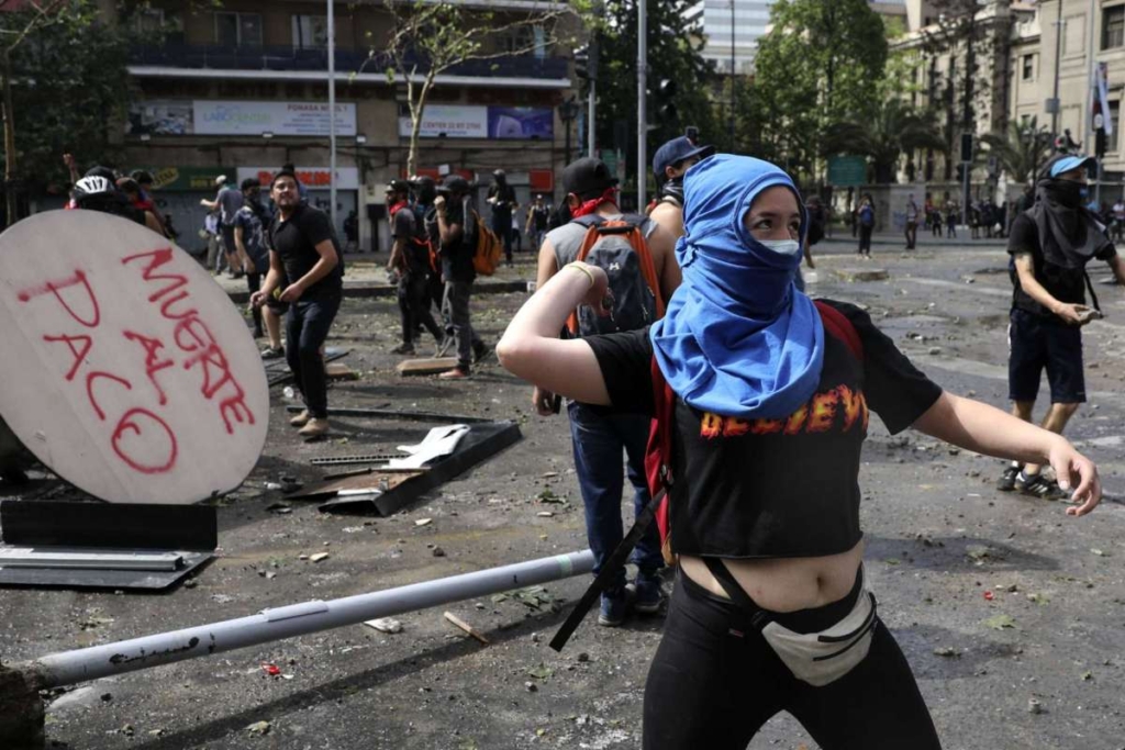 Protesters throw rocks at police during a protest in Santiago, Chile, Wednesday, 23 October 2019. Rioting, arson attacks and violent clashes wracked Chile as the government raised the death toll to 15 in an upheaval that has almost paralyzed the South American country long seen as the region’s oasis of stability. Photo: Rodrigo Abd / AP Photo