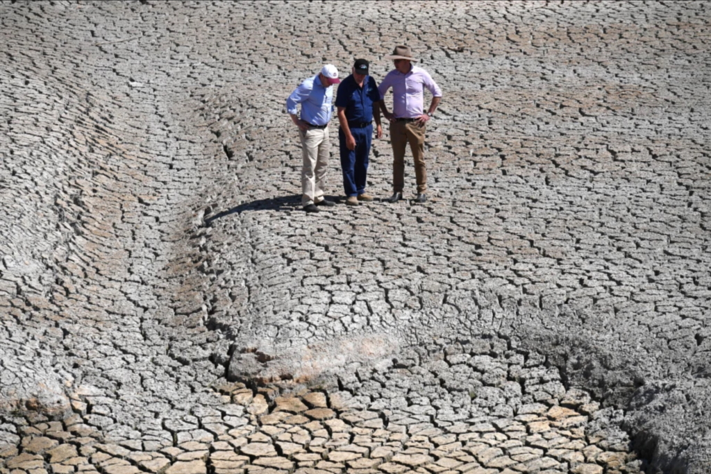 Treasurer Josh Frydenberg, orchard owner Dino Rizzato, and Water Resources Minister David Littleproud stand in a dried-up dam at Cottonvale apple orchard, outside the drought-ravaged town of Stanthorpe, 180km south-west of Brisbane. Photo: AAP