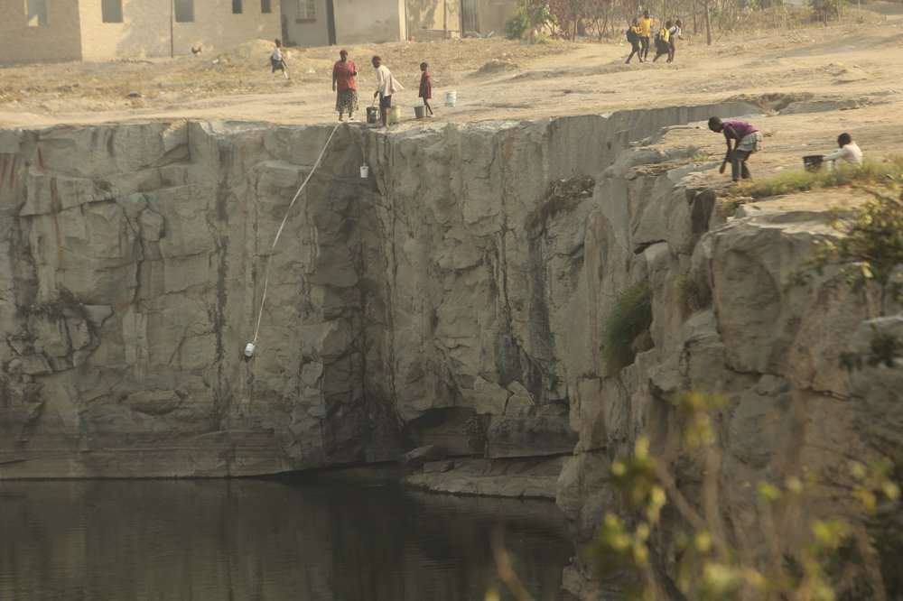Women and children use containers attached to rope to fetch water from a disused quarry in Harare, on 1 October 2019. Photo: Tsvangirayi Mukwazhi / Associated Press