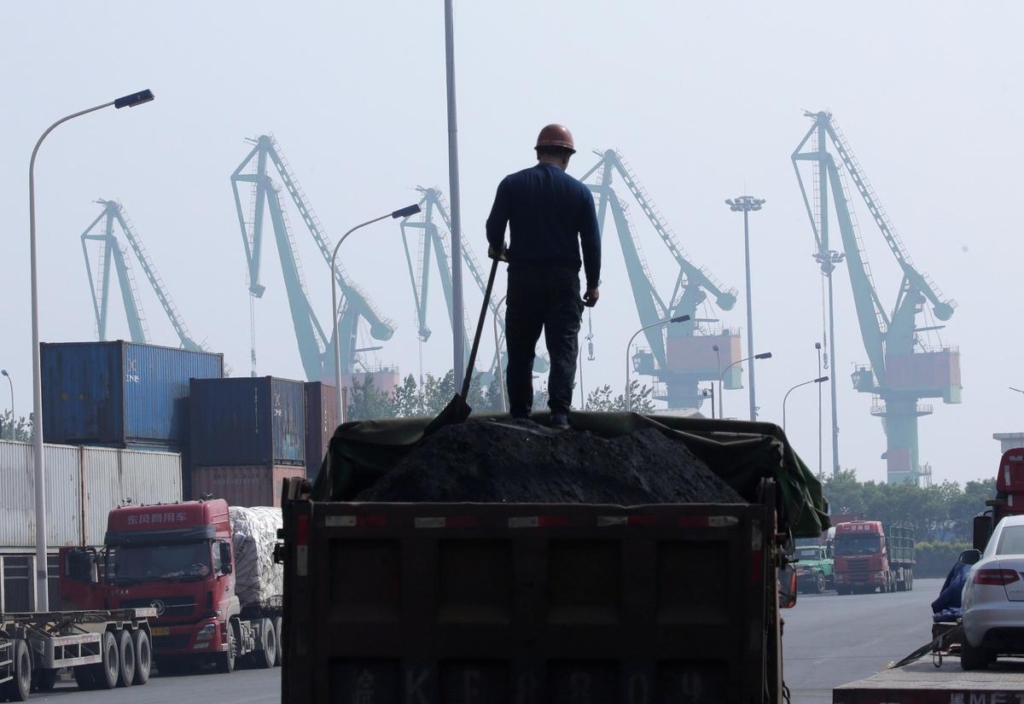 A worker loads coal in a truck next to containers outside a logistics center near Tianjin Port, in northern China, 16 May 2019. Photo: Jason Lee / REUTERS