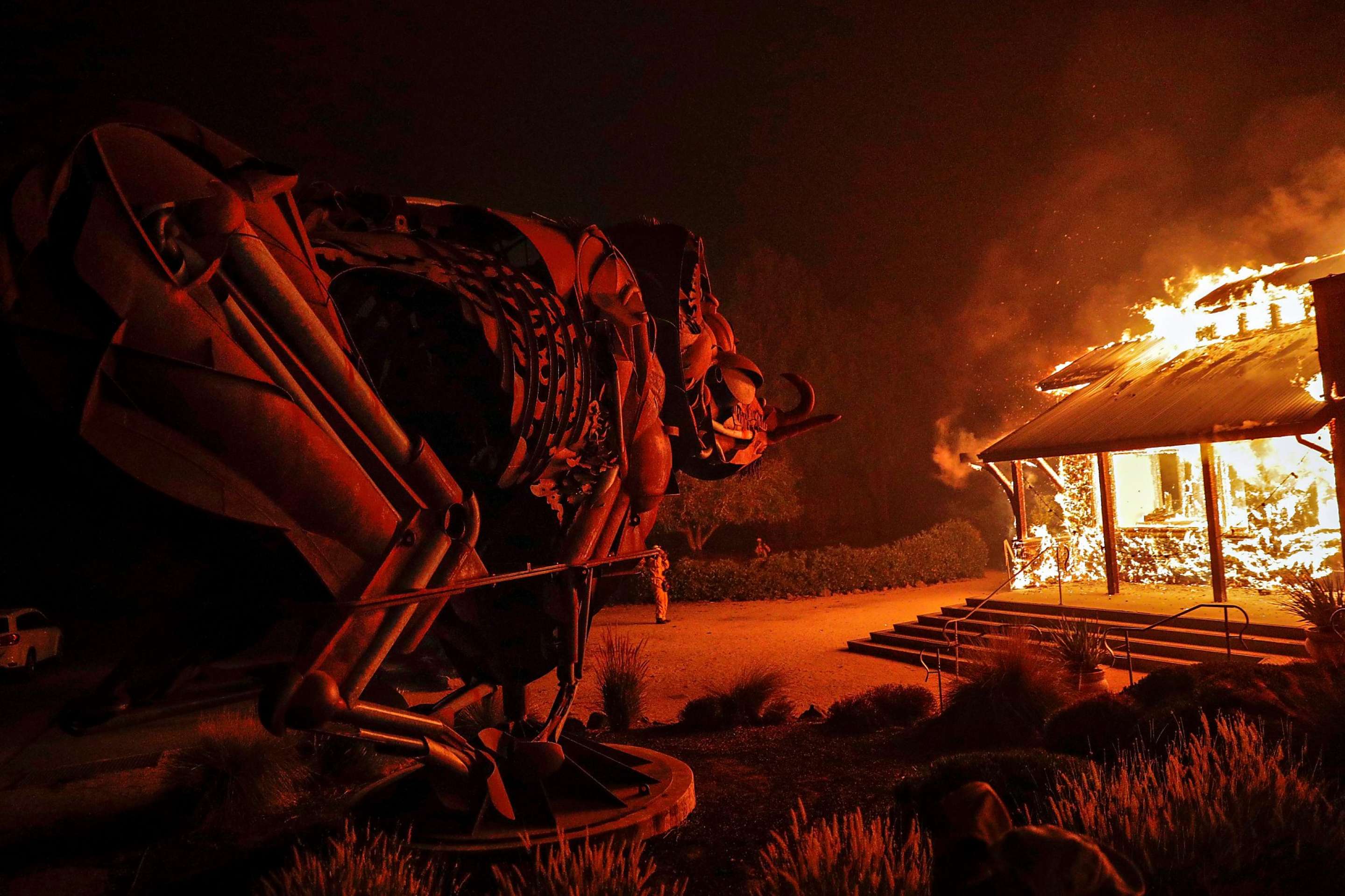 A house burns in the Kincade Fire on 23 October 2019 as a metal sculpture of an animal looks on. Photo: Carlos Avila Gonzalez / SF Chronicle