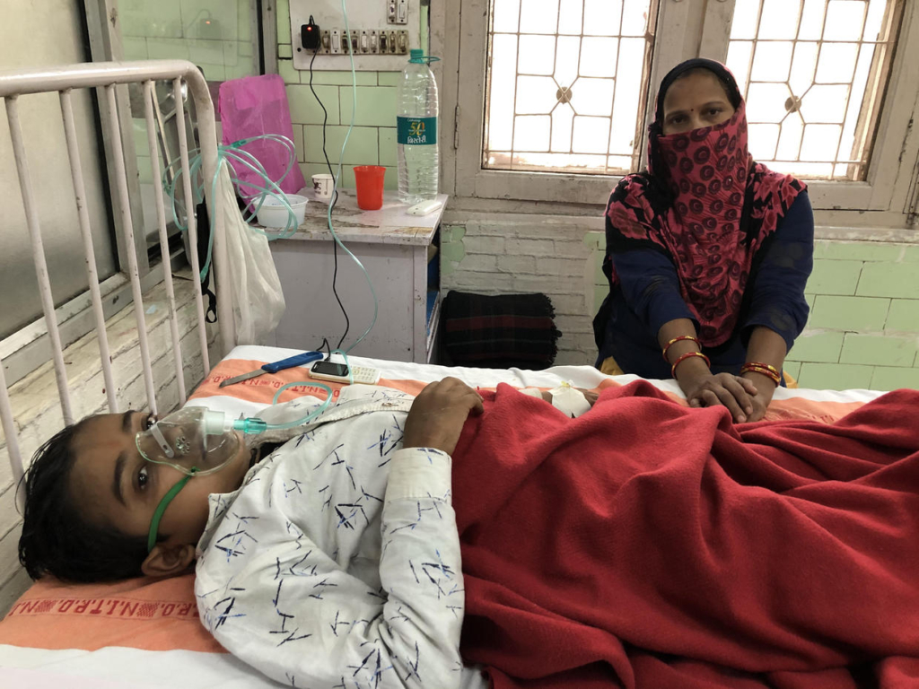 Sumit Kumar, 15, lays in a bed at India's National Institute of Tuberculosis and Respiratory Diseases in Delhi, 14 November 2019, where he has been receiving treatment for a lung infection, while his mother mother Seema Kumari keeps him company. Dangerous air pollution in India forced Delhi schools to close for the second time in two weeks. Photo: Arshad R. Zargar / CBS