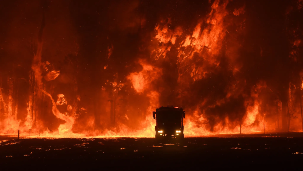 Firefighters are overwhelmed by flames at a bushfire in Orangeville, west of Campbelltown, 6 December 2019. The Sydney Morning Herald’s Chief Photographer Nick Moir, who was at the scene, said the fire advanced so quickly everyone was forced to “run from its path”. He said a lone fire truck held at the scene as long as possible before the ferocity of the flames forced the firefighters to retreat. Photo: Nick Moir / The Sydney Morning Herald