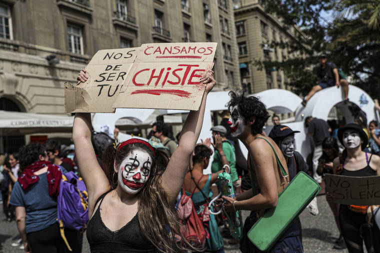 A woman holds a sign that reads in Spanish “We are tired of being your joke” as Artists, clowns, mimes and actors protest against President Sebastian Piñera’s government, at the Plaza de Armas in Santiago, Chile, Wednesday, 23 October 2019. Rioting, arson attacks and violent clashes wracked Chile as the government raised the death toll in an upheaval that has almost paralyzed the South American country long seen as the region's oasis of stability. Photo: Esteban Felix / AP Photo