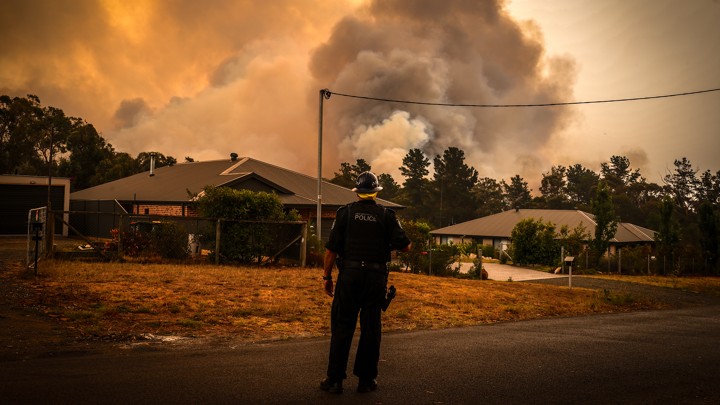 A policeman watches bushfires as they approach homes located on the outskirts of the town of Bargo on 21 December 2019 in Sydney, Australia. A catastrophic fire danger warning was issued for the greater Sydney region, the Illawarra and southern ranges as hot, windy conditions continued to hamper firefighting efforts across NSW. NSW Premier Gladys Berejiklian declared a state of emergency on Thursday, the second state of emergency declared in NSW since the start of the bushfire season. Photo: David Gray / Getty Images