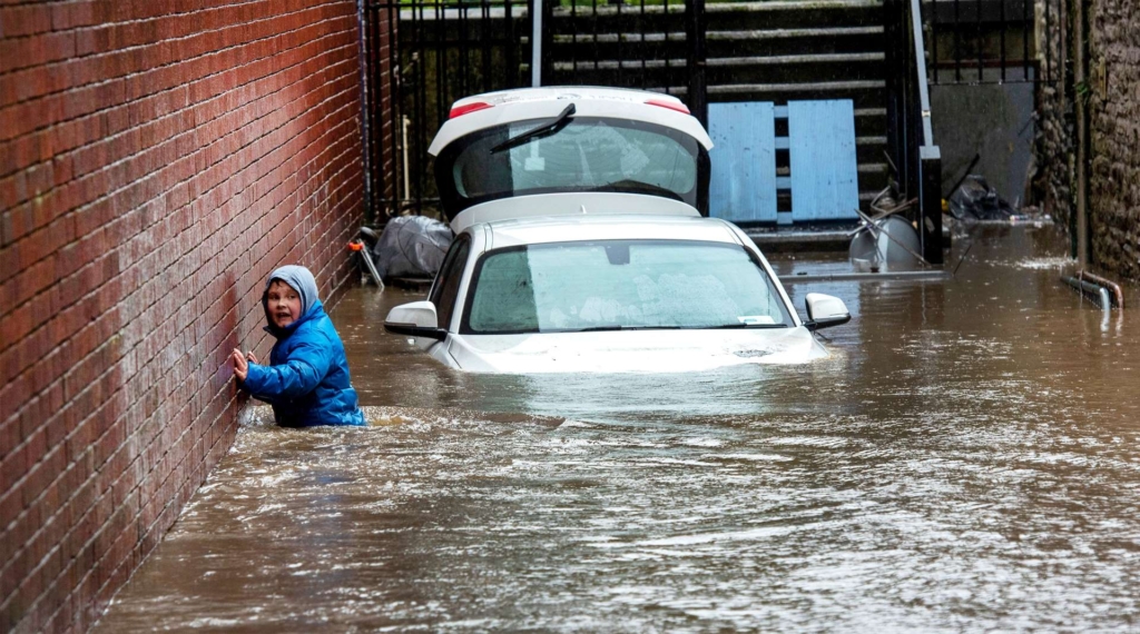 A boy wades through a flooded alleyway in Pontypridd, South Wales, on 16 February 2020. Photo: Neil Munns / EPA-EFE / Shutterstock