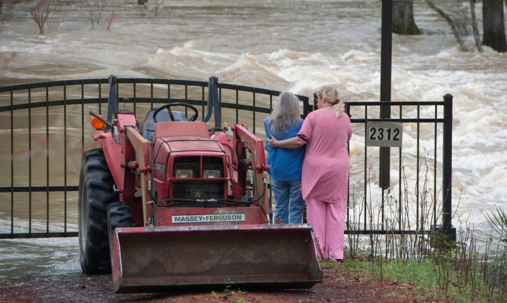 Kathy Covington, center, watches the powerful floodwaters of the Pearl River rush through her Florence, Mississippi, yard on 16 February 2020. Photo: Barbara Gauntt / Clarion Ledger