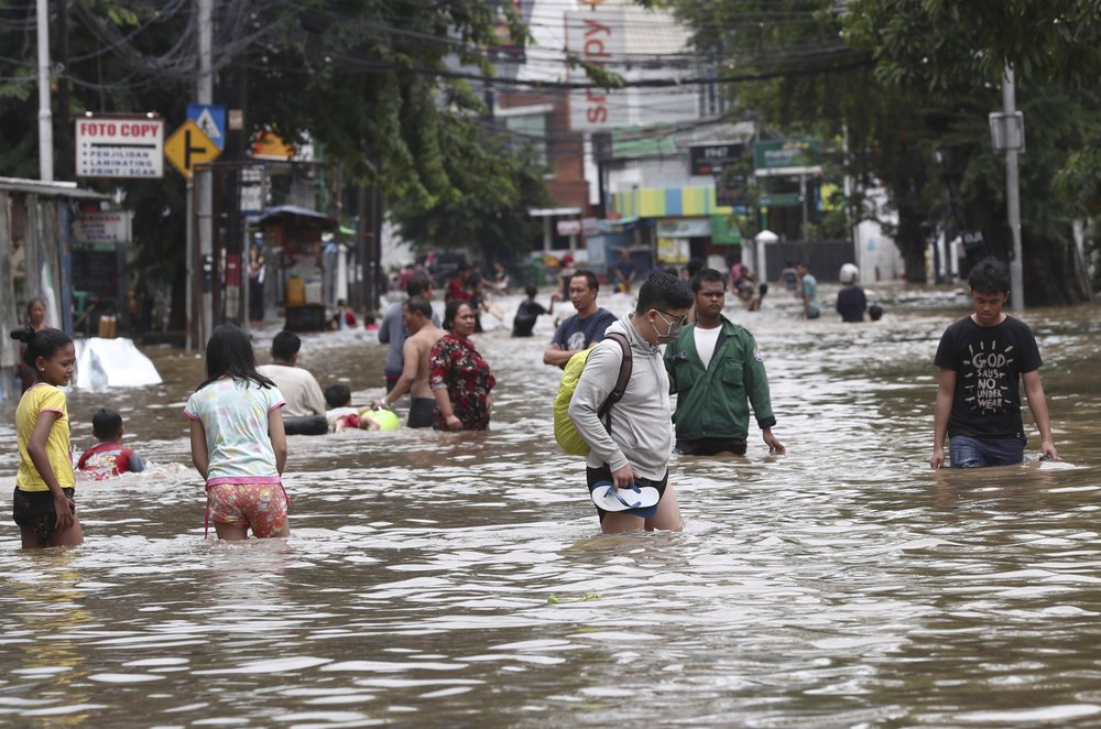 Indonesians wade through flood water on a street in Jakarta, Indonesia, Tuesday, 25 February 2020. Overnight rains caused rivers to burst their banks in greater Jakarta sending muddy water into residential and commercial areas, inundating thousands of homes and paralyzing parts of the city's transport networks, officials said. Photo: Tatan Syuflana / AP Photo