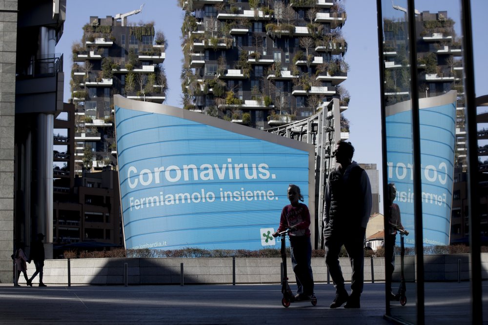 A man and a girl on a scooter are backdropped by a Lombardy region campaign advertising, reading in Italian, “Coronavirus. Let’s stop it together”, at the Porta Nuova business district in Milan, Wednesday, 11 March 2020. Italy is mulling even tighter restrictions on daily life and has announced billions in financial relief to cushion economic shocks from the coronavirus. For most people, the new coronavirus causes only mild or moderate symptoms, such as fever and cough. For some, especially older adults and people with existing health problems, it can cause more severe illness, including pneumonia. Photo: Luca Bruno / AP Photo