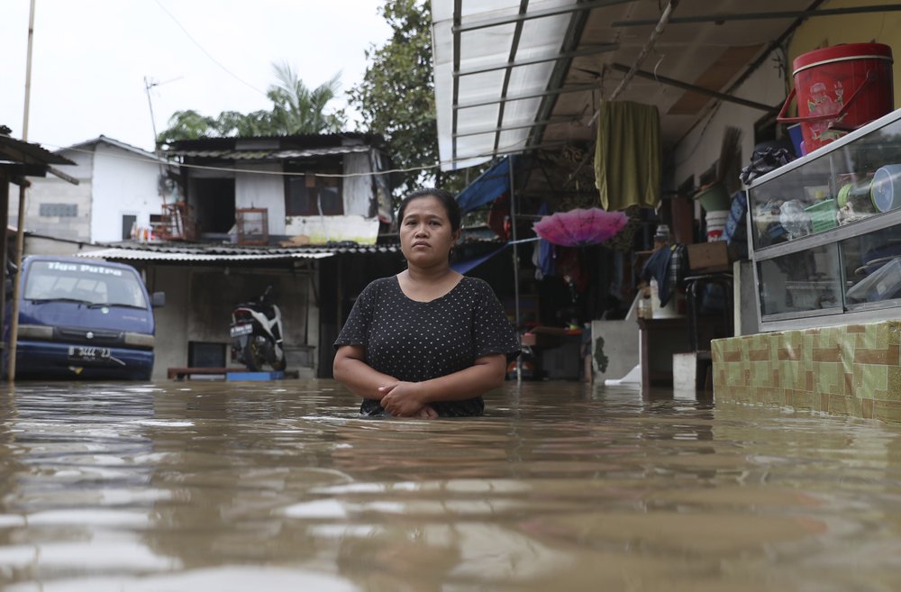 A woman pauses as she stands in flood water at a flooded neighborhood in Jakarta, Indonesia, Tuesday, 25 February 2020. Overnight rains caused rivers to burst their banks in greater Jakarta sending muddy water into residential and commercial areas, inundating thousands of homes and paralyzing parts of the city's transport networks, officials said. Photo: Achmad Ibrahim / AP Photo