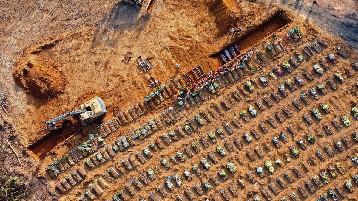 Aerial view of coffins being buried at an area where new graves have been dug at the Parque Tarumã cemetery in Manaus, Brazil, in April 2020. On 26 April 2020, 140 bodies of people killed by COVID-19 were laid to rest in Manaus, the jungle-flanked capital of Amazonas state. Normally the figure would be closer to 30 – but these are no longer normal times. Photo: Michael Dantas / AFP / Getty Images