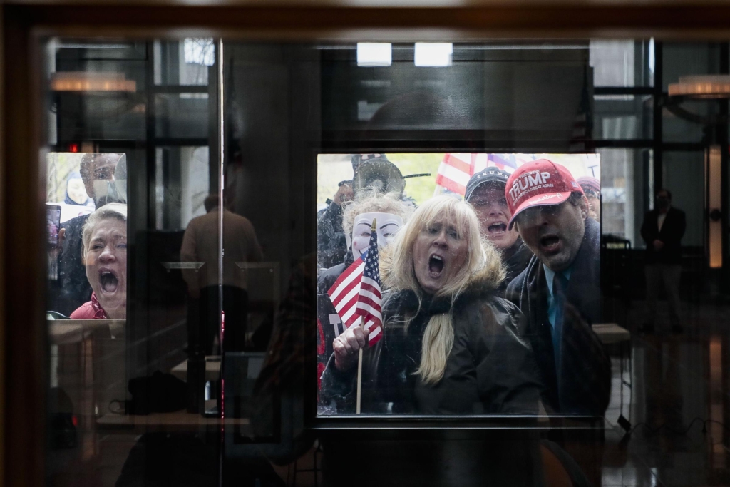 Protesters shout outside the Ohio Statehouse Atrium where reporters listen during state officials’ coronavirus update Monday, 13 April 2020. About 100 demonstrators assembled outside the building, upset that the state remains under a stay-at-home order and that non-essential businesses remain closed. Photo: Joshua A. Bickel / Dispatch