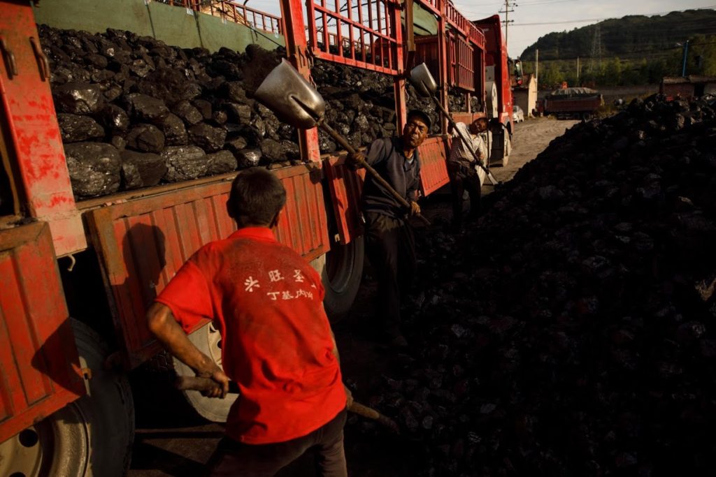 Workers shovel coal onto a truck in Huating, China, on 18 September 2020. Photo: Thomas Peter / Reuters