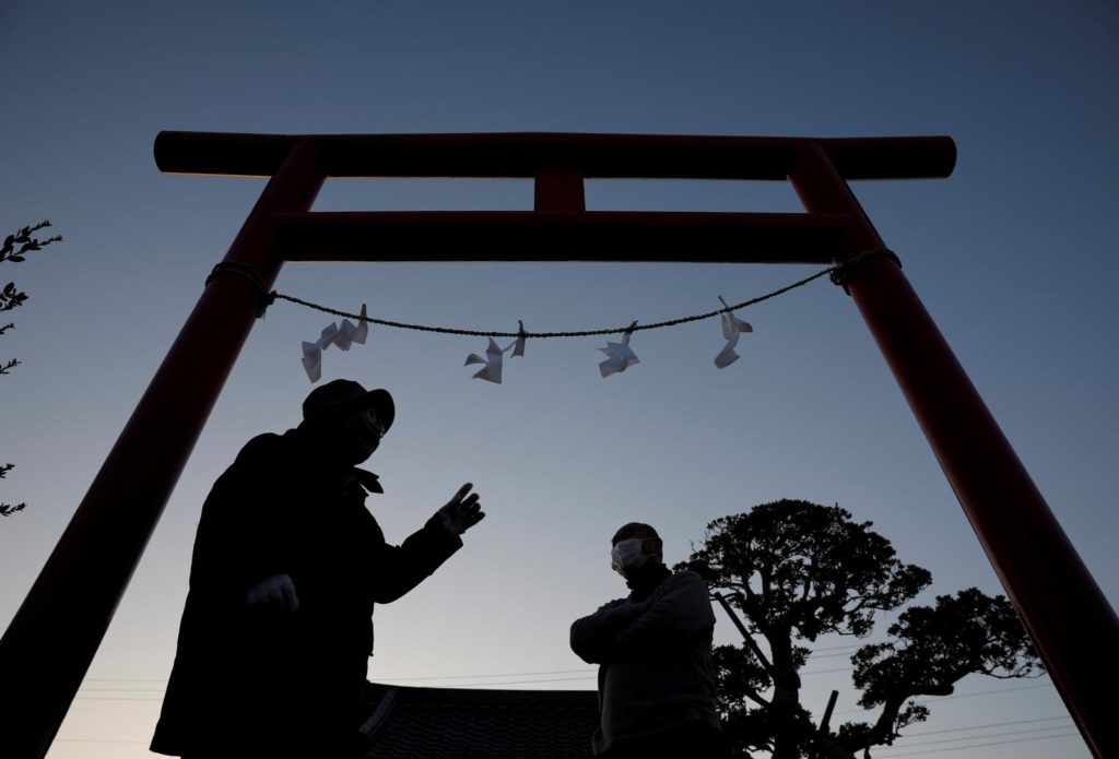 Residents of Hisanohama change Gohei, paper offering to a god in the Shinto ritual, on a torii gate in front of a memorial monument for the victims of the 2011 earthquake and tsunami at Akiba shrine ahead of its ten years anniversary in Iwaki, Japan, 10 March 2021. Photo: Kim Kyung-Hoon / REUTERS