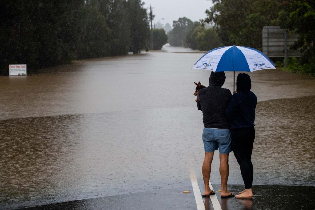 Two people stand at the edge of the flooded Pitt town road in the town of Windsor, near Sydney, Australia as the state of New South Wales experiences widespread flooding and severe weather, 21 March 2021. Photo: Edwina Pickles
