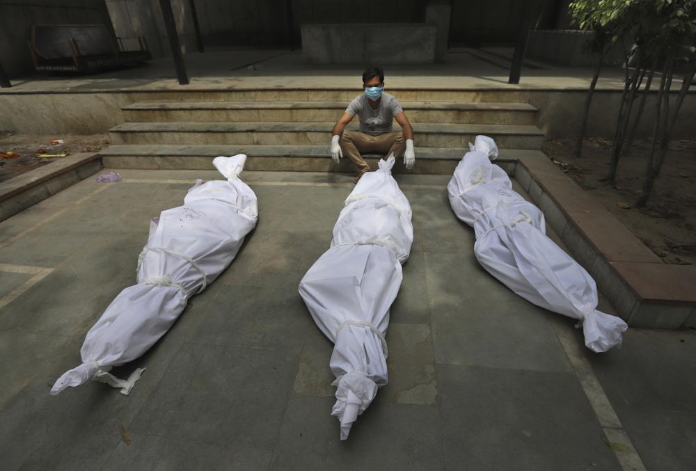 A man waits for the cremation of a relative who died of COVID-19, placed near bodies of other victims, in New Delhi, India, Tuesday, 20 April 2021. India has been overwhelmed by hundreds of thousands of new coronavirus cases daily, bringing pain, fear and agony to many lives as lockdowns have been placed in Delhi and other cities around the country. Photo: AP Photo