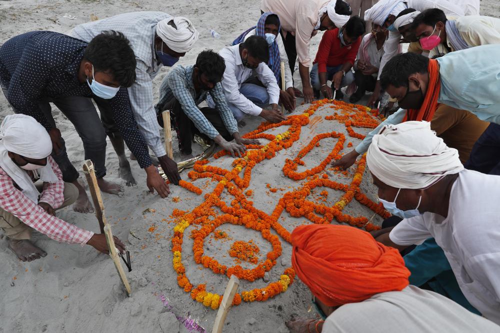 Family members and relatives bow their heads as they pray after burying a person who died of reasons other than COVID-19 in a shallow sand grave on the banks of river Ganges in Prayagraj, India, Sunday, 16 May 2021. Police are reaching out to villagers in northern India to investigate the recovery of bodies buried in shallow sand graves or washing up on the Ganges River banks, prompting speculation on social media that they were the remains of COVID-19 victims. Photo: Rajesh Kumar Singh / AP Photo