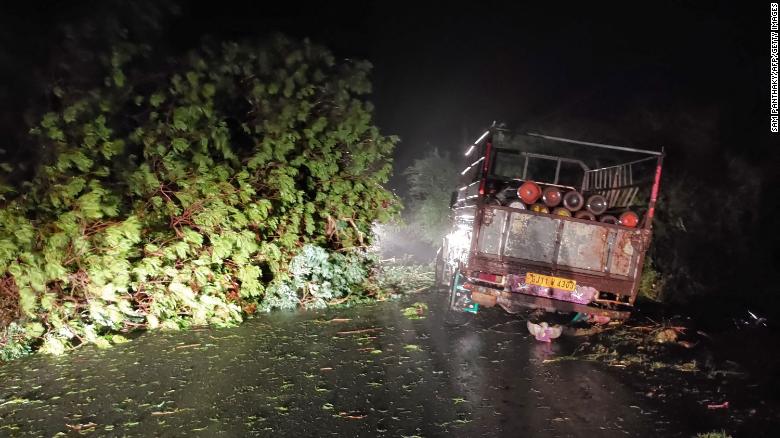 A truck loaded with oxygen cylinders is blocked by trees felled by Cyclone Tauktae, near Mahuva in Gujarat state, India, on 17 May 2021. Photo: Sam Panthaky / AFP / Getty Images