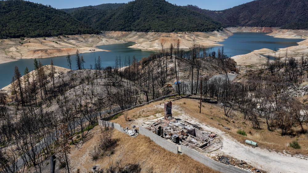 A home destroyed in the 2020 North Complex Fire sits above Lake Oroville on 23 May 2021, in Oroville, California. At the time of this photo, drought had reduced the reservoir to 39 percent of capacity and 46 percent of its historical average. Photo: Noah Berger / AP Photo