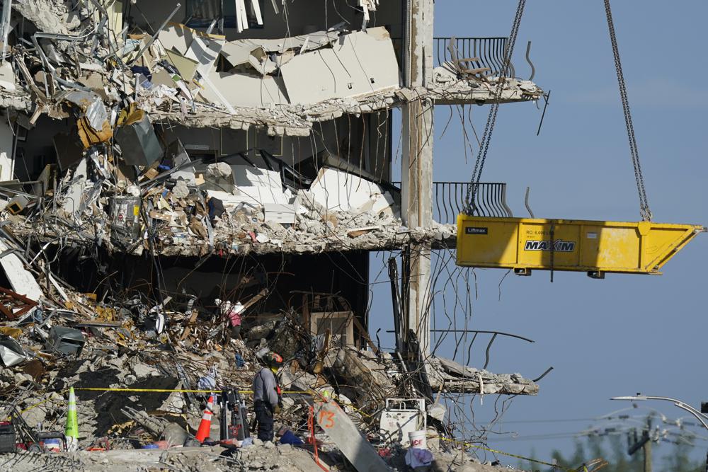 A crane is used to remove sets of human remains, as search and rescue personnel work atop the rubble at the Champlain Towers South condo building, where scores of people remain missing more than a week after it partially collapsed, 2 July 2021, in Surfside, Florida. Rescue efforts resumed Thursday evening after being halted for most of the day over concerns about the stability of the remaining structure. Photo: Mark Humphrey / AP Photo