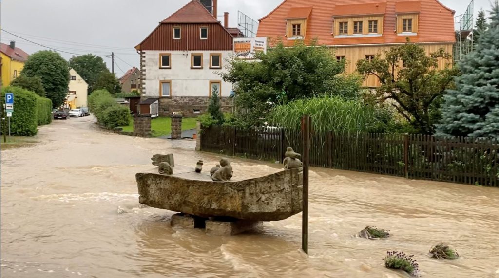 Floodwater flows down a road and around a boat sculpture following record rainfall in Reinhardtsdorf-Schona, Saxony, Germany 17 July 2021 in this still image taken from social media video filmed on 17 July 2021 obtained by REUTERS. Photo: REUTERS