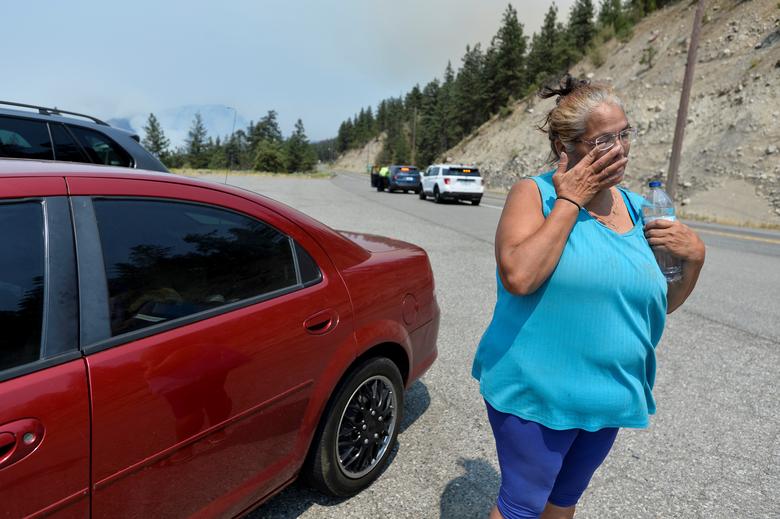 Martha Van Dyke of Lytton stands outside of her car after a wildfire that raged through her town and forced residents to evacuate, outside of Lytton, British Columbia, Canada, 1 July 2021. Photo: Jennifer Gauthier / REUTERS