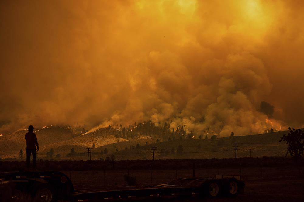 A truck driver who hauls fire equipment watches as the Sugar Fire, part of the Beckwourth Complex Fire, burns in Doyle, California, on 10 July 2021. Photo: Noah Berger / AP Photo