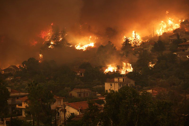 Flames rise near houses as a wildfire burns in the village of Gouves, on the island of Evia, Greece, 8 August 2021. Thousands of people have fled their homes on the Greek island wildfires burned uncontrolled for a sixth day on Sunday, and ferries were on standby for more evacuations after taking many to safety by sea. REUTERS / Stringer